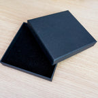 An open black box with a dark interior sits on a wooden surface.
